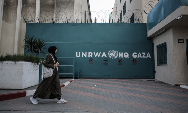 سيدة تمر من أمام وكالة "أونروا" في غزة (الأناضول)