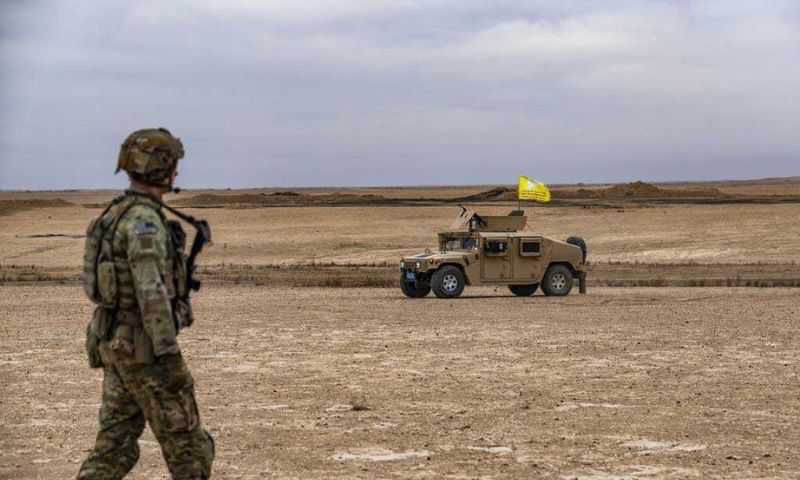 جندي أمريكي يمشي بالقرب من آلية عسكرية لـ"قوات سوريا الديمقراطية" خلال مناورات مشتركة بين هذه القوات والتحالف الدولي في ريف دير الزور- 7 من كانون الأول 2022 (AFP)