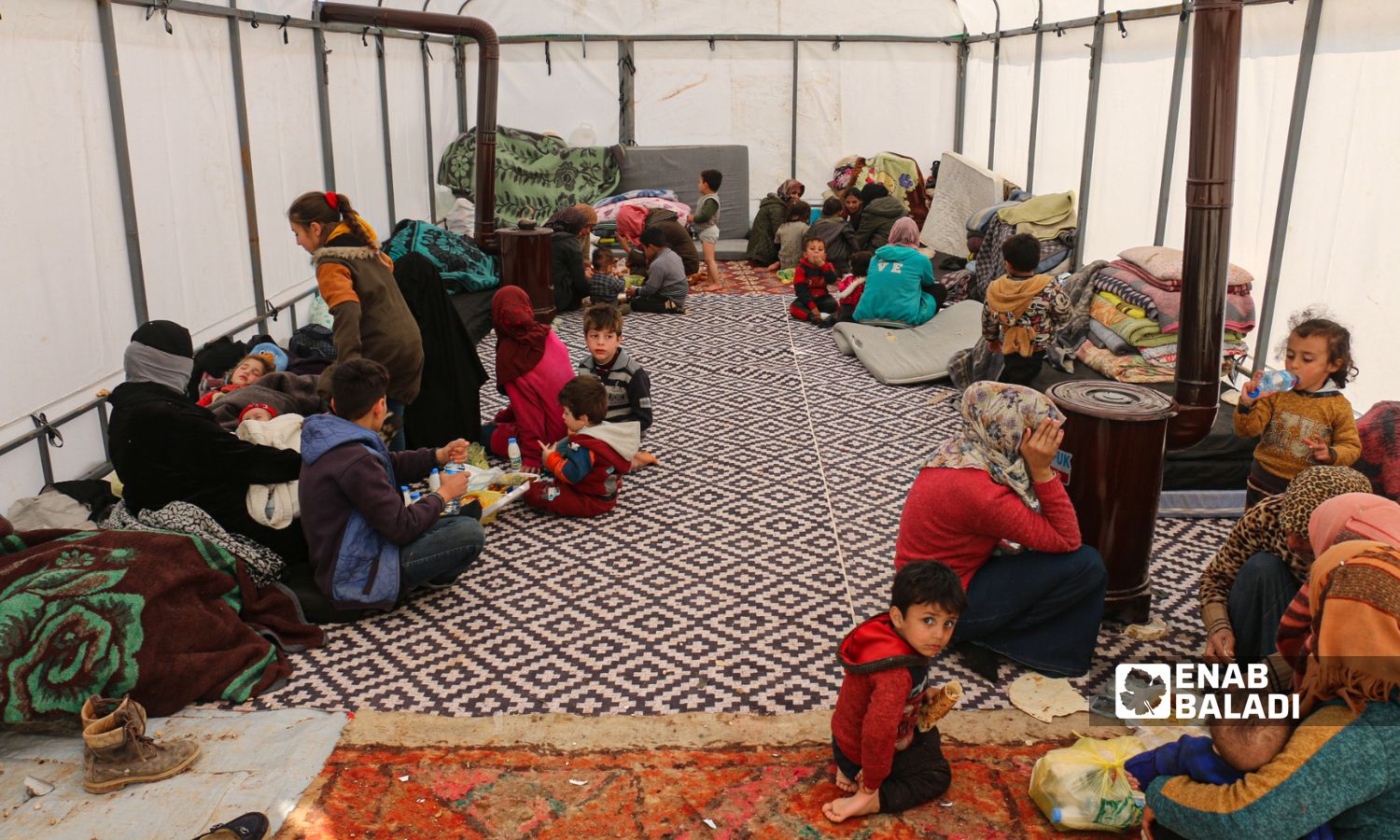 عائلات تقطن داخل خيمة كمركز إيواء في بلدة جنديرس بريف حلب الشمالي متضررة من الزلزال الذي ضرب جنوبي تركيا ومناطق متفرقة في سوريا- 13 شباط 2023 (عنب بلدي/ ديان جنباز)