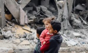 أطفال يسيرون بين ركام المنازل والمباني التي دمرها القصف الإسرائيلي في رفح، جنوبي قطاع غزة- 24 من آذار 2024 (رويترز)