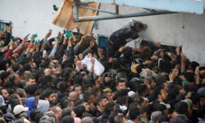 فلسطينيون يتجمعون للحصول على مساعدات من "أونروا" في ظل تردي الوضع الإنساني ومجاعة تهدد مئات آلاف الأهالي بسبب حصار إسرائيلي مطبق للقطاع- 18 من آذار 2024 (رويترز)