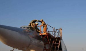 طيارون روس يتعاملون طائرة حربية روسية في قاعدة حميميم الجوية بريف محافظة اللاذقية على الساحل السوري (سبوتنيك)
