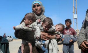 سيدة فلسطينية تهرب من مستشفى الشفاء عقب غارة إسرائيلية، مع أطفالها الثلاثة، نحو الجنوب، في وسط غزة- 21 من آذار 2024 (رويترز)