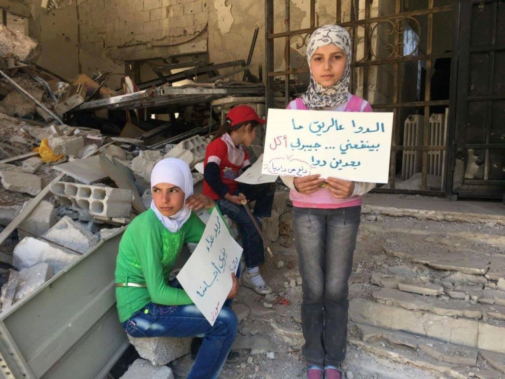 “Medication to empty stomach does not do me good… bring me food, so I can have medication”. Children waiting for the promised aid convoy. Image source: Local Council of Daraya City.