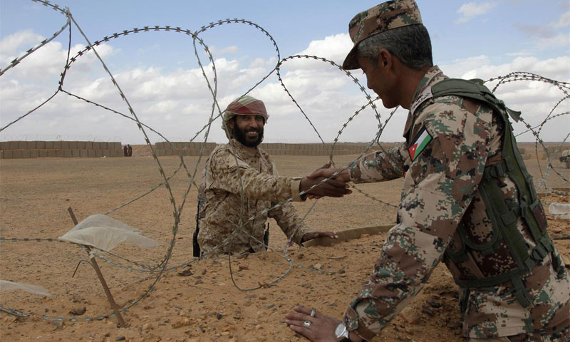 A Syrian soldier from the Army of Free Tribes shakes hands with a Jordanian soldier at the border at al-Rukban camp, 14 February 2017 (AP)