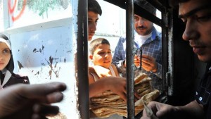 Syrians buy bread at a bakery in the northern city of Aleppo on August 19, 2012, on the first day of the Eid al-Fitr, marking the end of the holy fasting month of Ramadan.  Syrian helicopters have dropped leaflets over the city urging residents not to shelter rebels and warning the Free Syrian Army it had one last chance to surrender. AFP PHOTO/BULENT KILIC        (Photo credit should read BULENT KILIC/AFP/GettyImages)