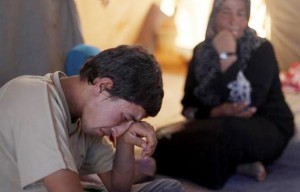 In this Tuesday, Sept. 11, 2012 photo, Basel Baradan, an 18-year-old farmer who fled his southern restive border town of Daraa, Syria with his family in July, wipes his eyes as he speaks during an interview at the Zaatari Refugee Camp, in Mafraq, Jordan. Jordan now hosts 200,000 Syrians, the largest number of refugees of any neighboring country. After months of delay, Jordan finally opened its first official refugee camp in July at Zaatari, near the border with Syria.(AP Photo/Mohammad Hannon)