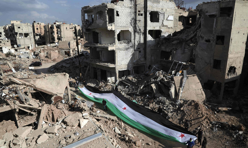 ناشطون يرفعون علم الثورة السورية بين الأبنية المهدمة جراء القصف في حي جوبر بدمشق - 3 آذار 2016 (عامر الموهباني ـ AFP)