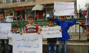 أطفال يحملون لافتات في مظاهرة بمدينة عامودا، عنب بلدي.