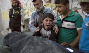 A Syrian boy is comforted as he cries next to the body of a relative who died in a reported airstrike on April 27, 2016 in the rebel-held neighbourhood of al-Soukour in the northern city of Aleppo.  / AFP PHOTO / KARAM AL-MASRIKARAM AL-MASRI/AFP/Getty Images