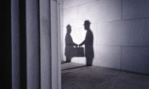 Shadows of two men with briefcase shaking hands, side view