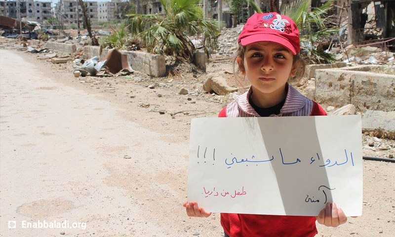 طفلة تحمل لافتة داخل مدينة داريا اليوم الخميس 12 أيار (عنب بلدي)