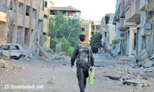 مقاتل في مدينة داريا بريف دمشق، وأمامه شجيرات خضراء بقيت في داريا (عنب بلدي)