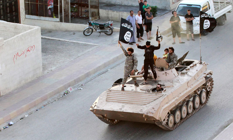 مقاتلون في تنظيم "الدولة الإسلامية" فوق دبابة في مدينة الرقة (أرشيفية)