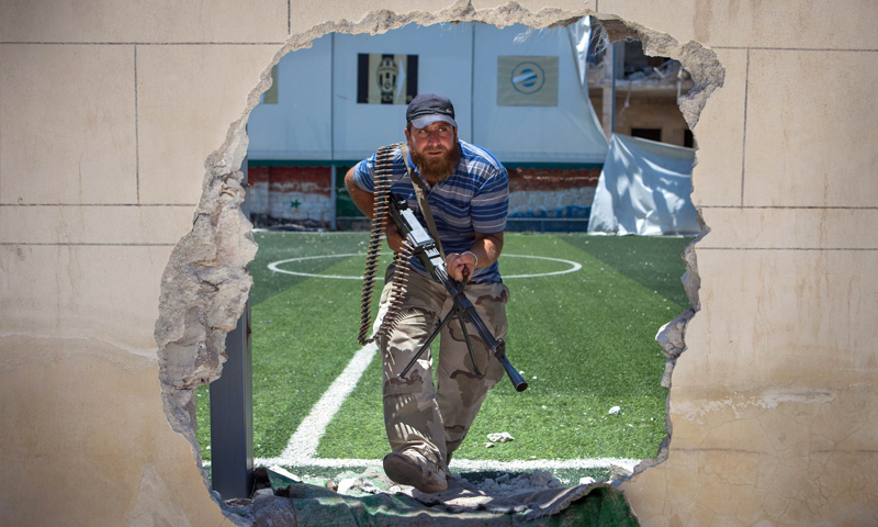 مقاتل في المعارضة السورية يمرّ عبر فتحة في الجدار (إنترنت)