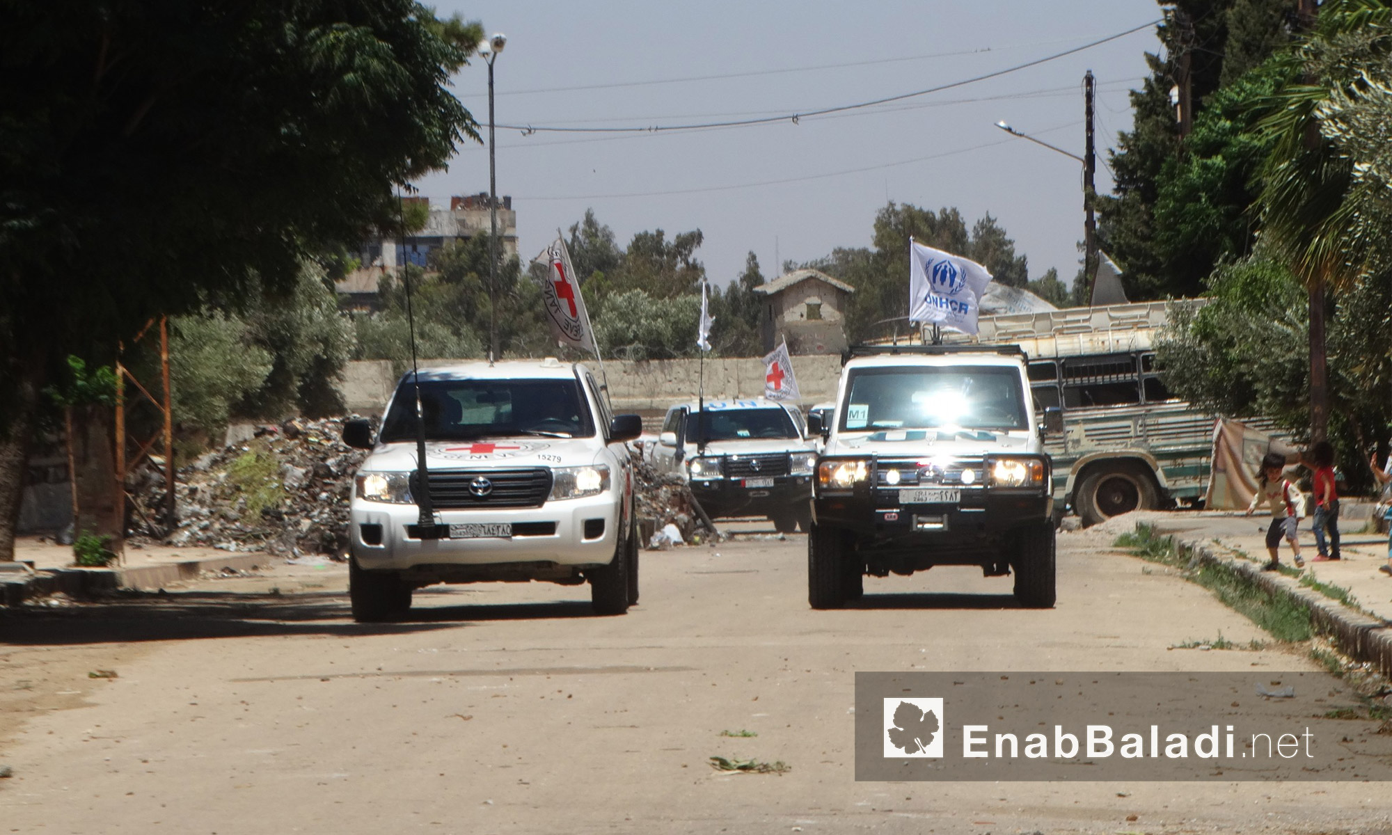 سيارات قافلة المساعدات الغذائية في حي الوعر بحمص - الاثنين 18 تموز (عنب بلدي)