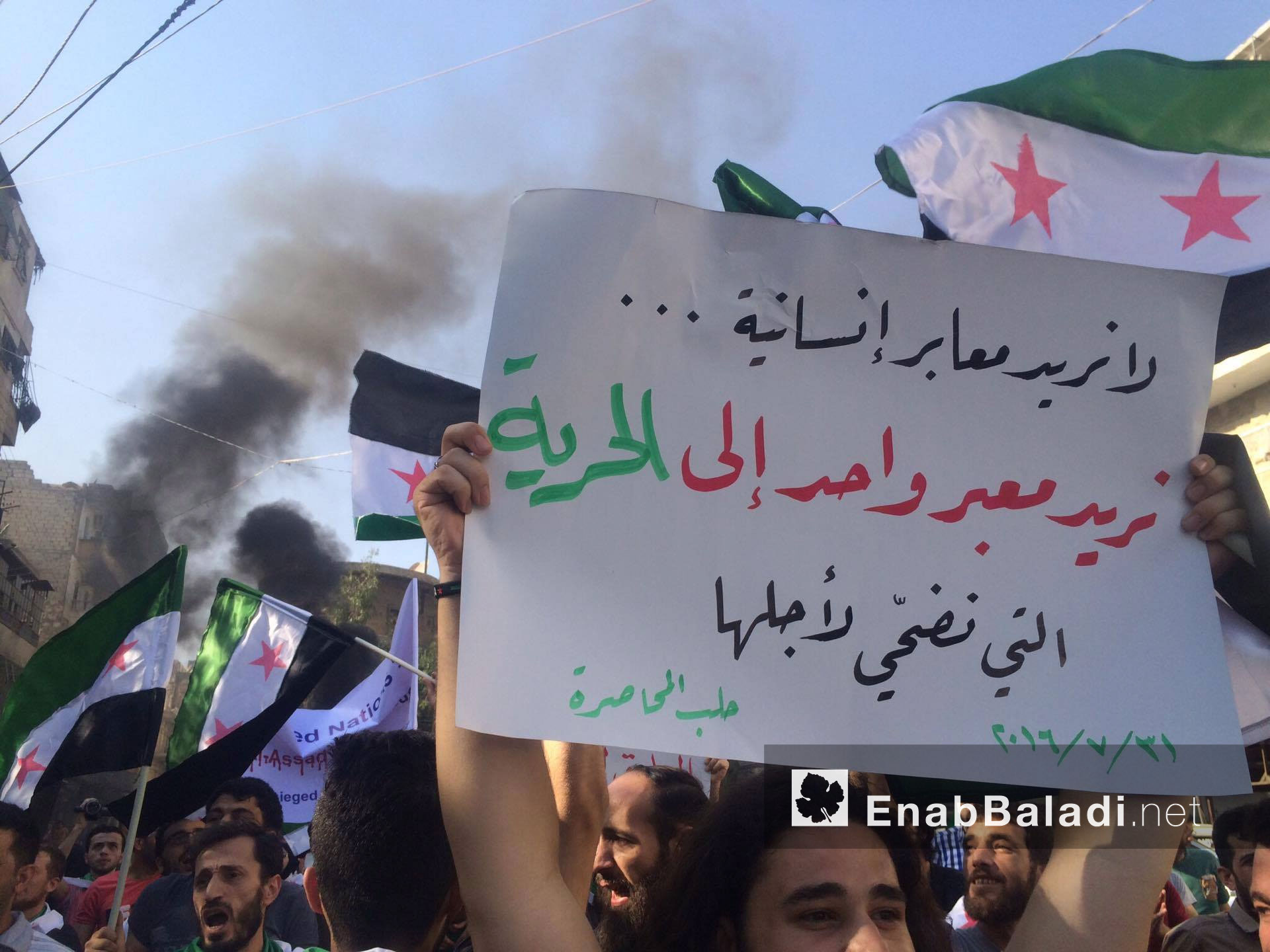 ناشط يرفع لافتة ترفض العبور من ممرات مفترضة أعلنت عنها موسكو في حلب - 31 تموز 2016 (عنب بلدي)