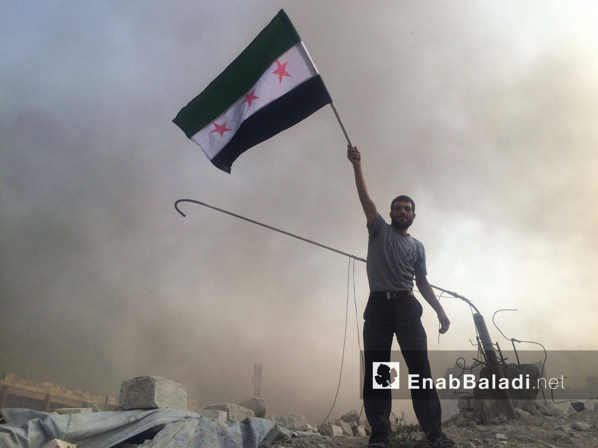 مواطن يرفع علم "الثورة السورية" في مدينة حلب - 31 تموز 2016 (عنب بلدي)