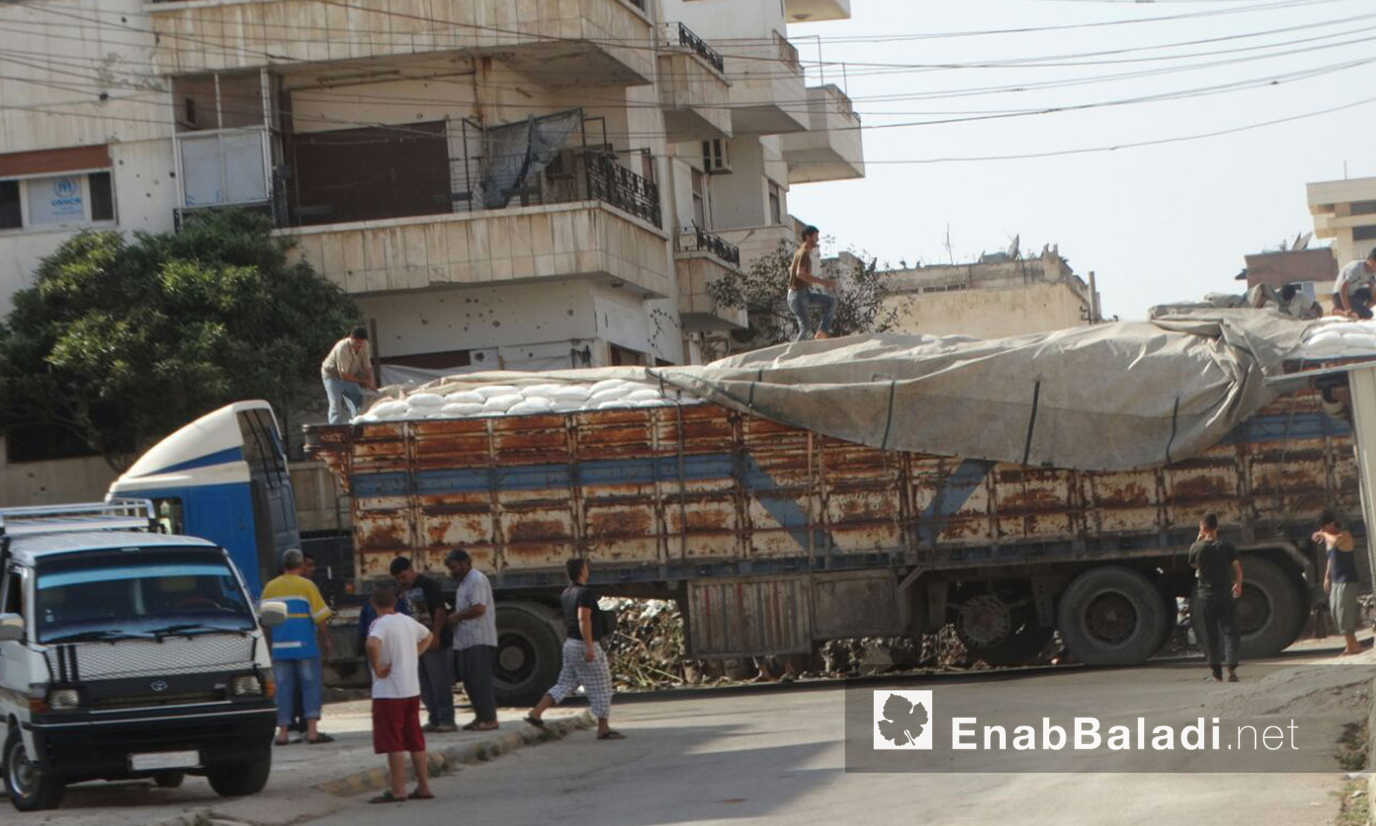 شاحنة تحوي أكياس ضمن قافلة المساعدات الإنسانية داخل حي الوعر المحاصر - الخميس 25 آب (عنب بلدي)
