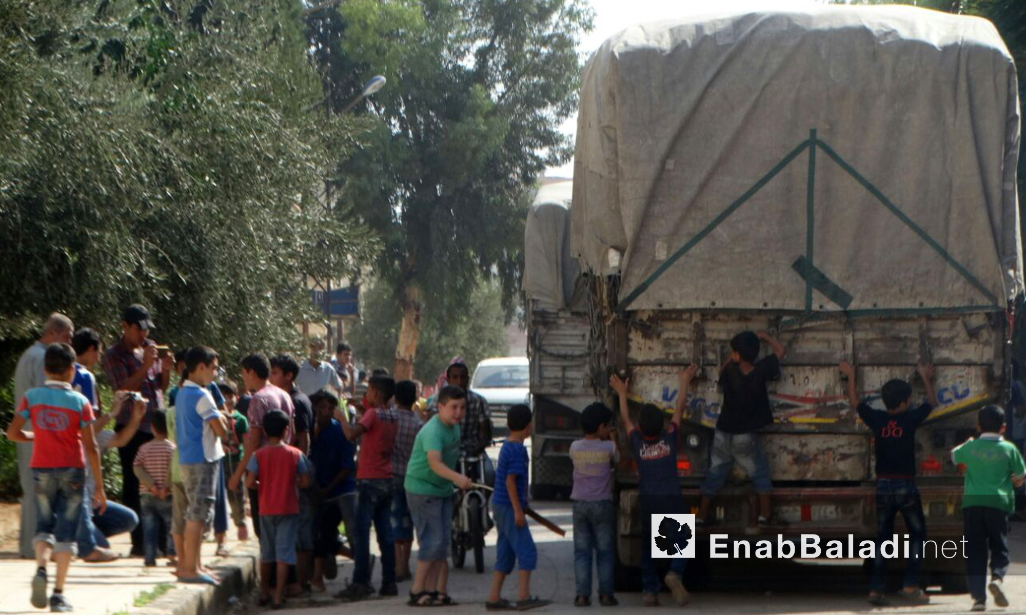 أطفال حي الوعر قرب شاحنات قافلة المساعدات - الثلاثاء 23 آب (عنب بلدي)