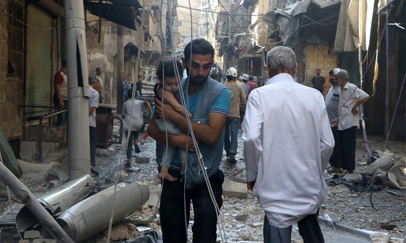 شاب مع ابنته نجوا من القصف على أحد أحياء حلب 22 آب (الأناضول)