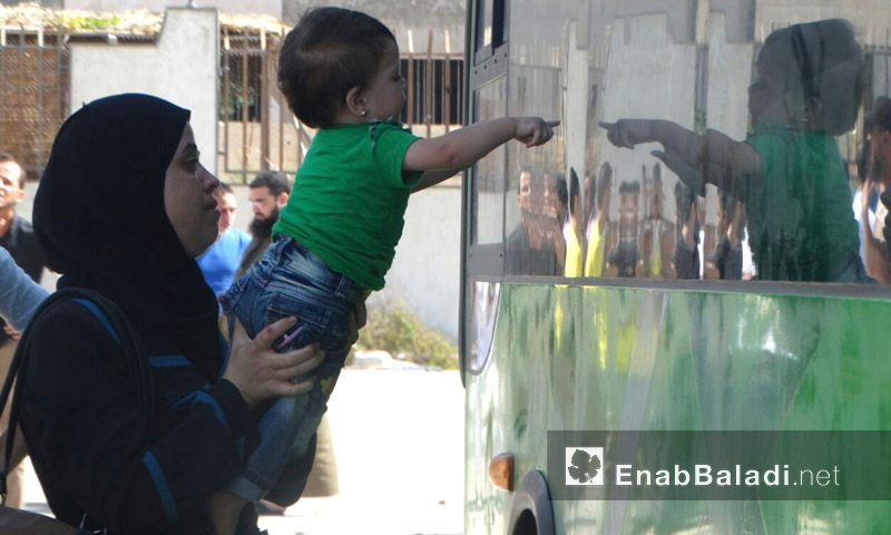 طفل يشير بإصبعه إلى المقاتلين داخل الباص في حي الوعر - الخميس 23 أيلول (عنب بلدي)