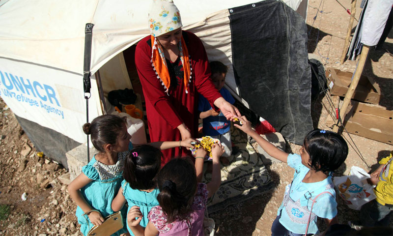 امرأة تقدم "السكاكر" لأطفال في مخيم للاجئين السوريين شمال العراق (رويترز)
