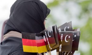 Eine verschleierte Frau tr‰gt am 27.05.2015 in Hanau (Hessen) zur Erˆffnung der neu fertiggestellten Bait-ul-Wahid Moschee der Ahmadiyya Muslim Jamad-Glaubensgemeinschaft (AMJ) deutsche und islamische F‰hnchen zu den G‰sten. Die Moschee verf¸gt ¸ber zwei zwˆlf Meter Hohe Zierminarette und bietet Platz f¸r rund 500 Menschen. Foto: Boris Roessler/dpa +++(c) dpa - Bildfunk+++ | Verwendung weltweit