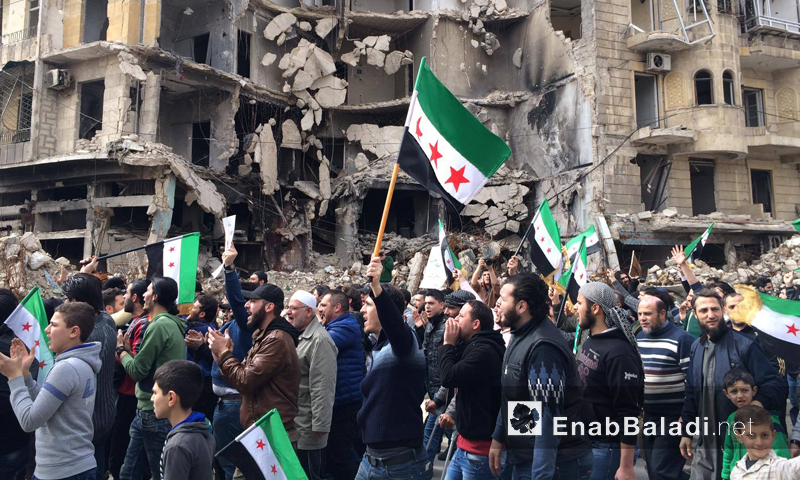متظاهرون يرفعون راية "الثورة السورية" في حلب - آذار 2016 (عنب بلدي)
