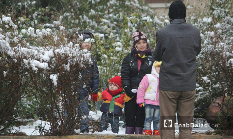 أب مع أطفاله في حي الوعر بحمص أثناء تساقط الثلوج_18 كانون الأول_(عنب بلدي)