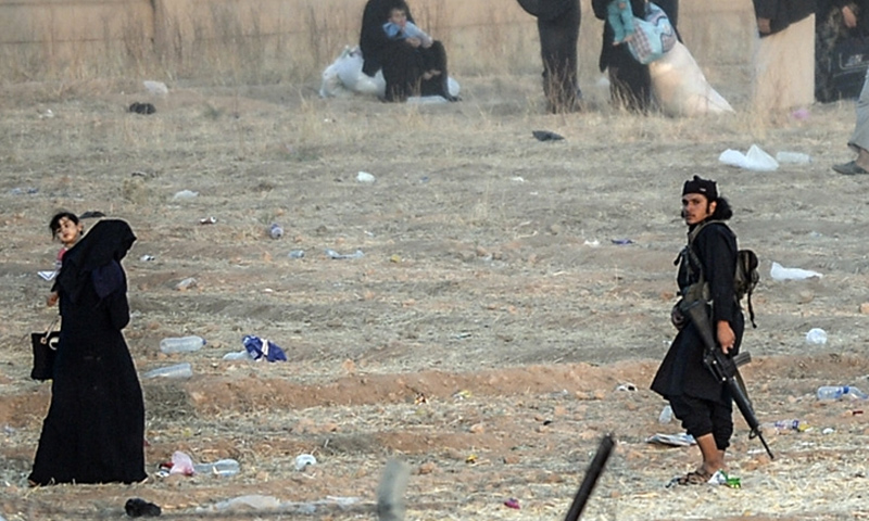 مقاتلون في تنظيم "الدولة الإسلامية" يحاولون إعادة النازحين على الشريط الحدودي مع تركيا في تل أبيض شمال الرقة - حزيران 2015 (إنترنت)