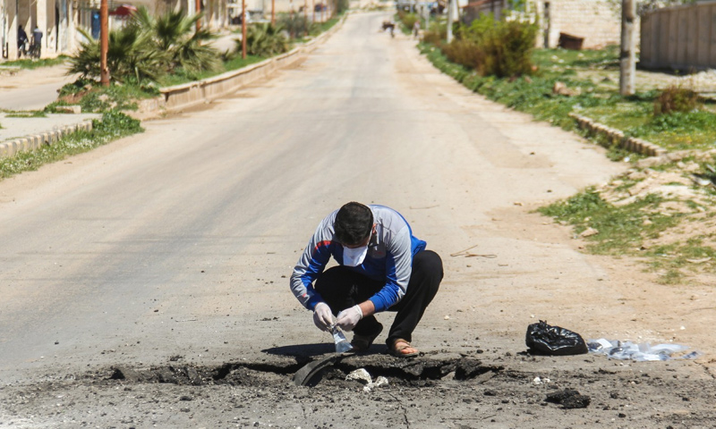 رجل سوري يجمع عينات من موقع الاستهداف الكيماوي في خان شيخون بريف إدلب- 7 نيشان-(AFP)