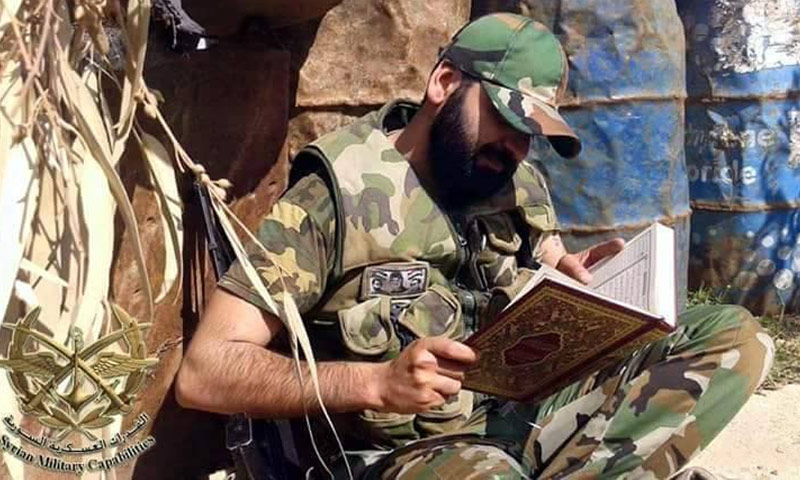 تعبيرية: عنصر من قوات الأسد يقرأ القرآن على الجبهات (صفحات موالية للنظام)