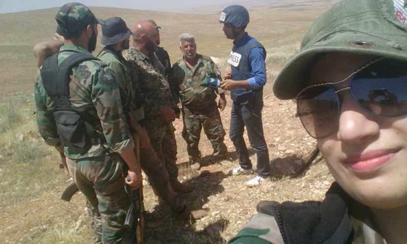 المراسلة سحر سويد إلى جانب عناصر من الدفاع الوطني في ريف حمص الشرقي - (فيس بوك)
