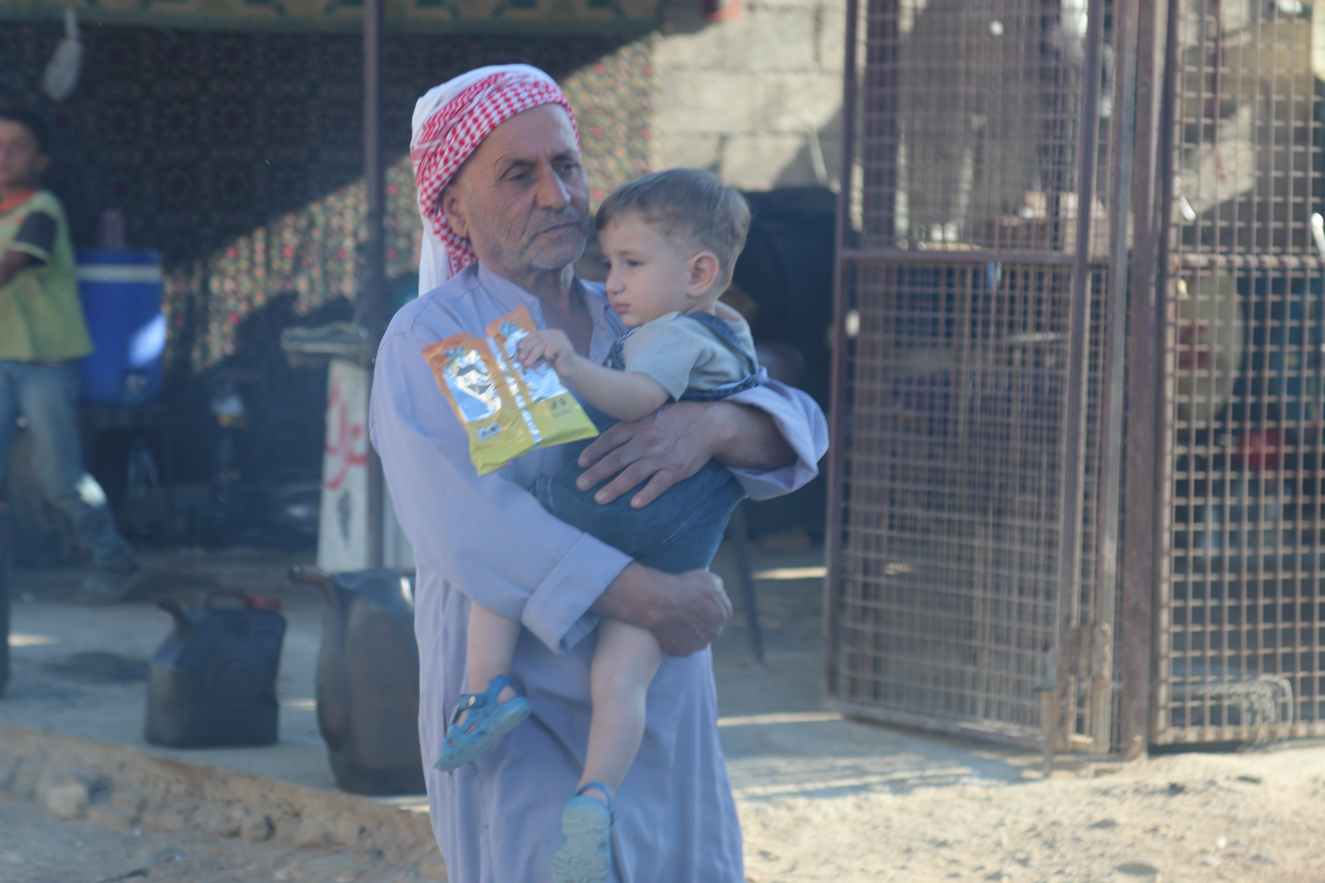 رجل يحمل حفيده في بلدة ملس بريف إدلب - 23 حزيران 2017 (عنب بلدي)