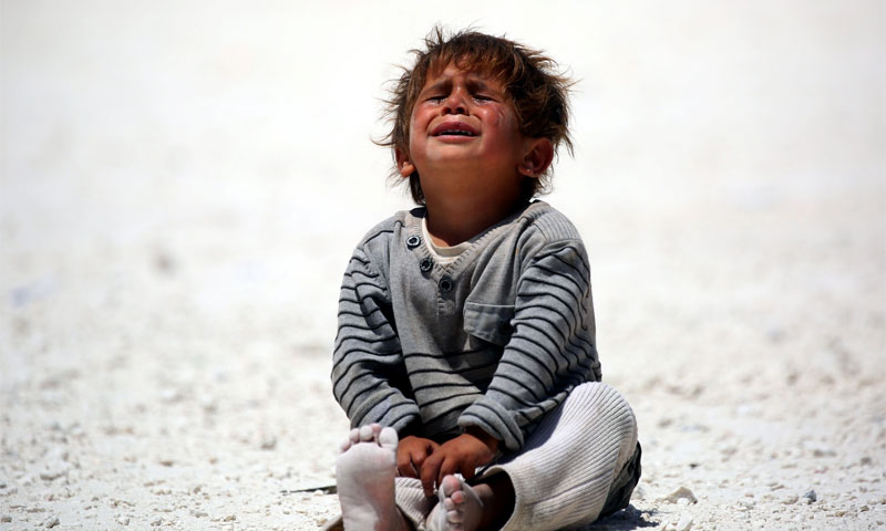 طفل سوري يبكي عقب فراره مع أسرته من الرقة إلى مخيم للنازحين في قرية عين عيسى (AFP)