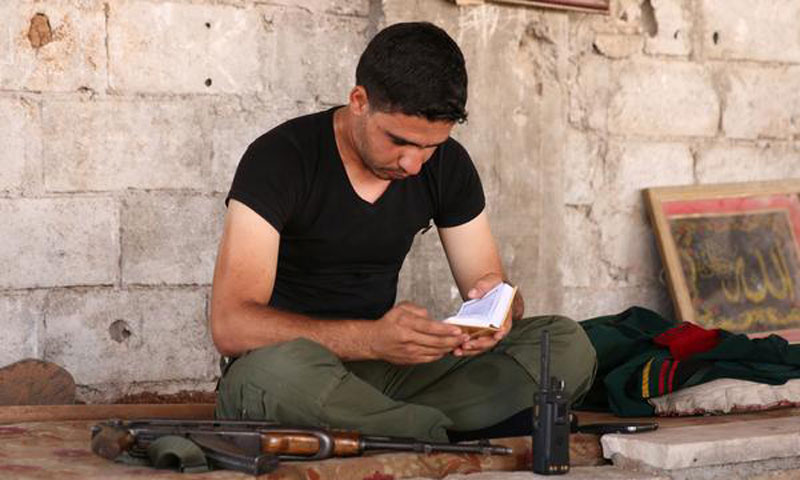 مقاتل في مدينة النعمية بمحافظة درعا يقرأ القرآن الكريم - 17 حزيران 2017 (رويترز)
