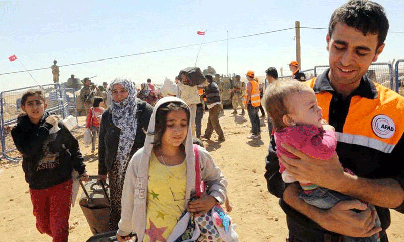 أحد كوادر منظمة "الإغاثة والكوارث الطبيعية" آفاد، في أحد مخيمات اللجئين السوريين في تركيا، ومعه طفل سوري (سوزجو)