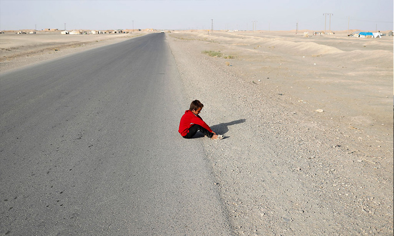 طفل نازح من مدينة الرقة يجلس على الطريق الرئيسي قرب بلدة الكرامة شرق الرقة - 7 حزيران 2017 - (رويترز)