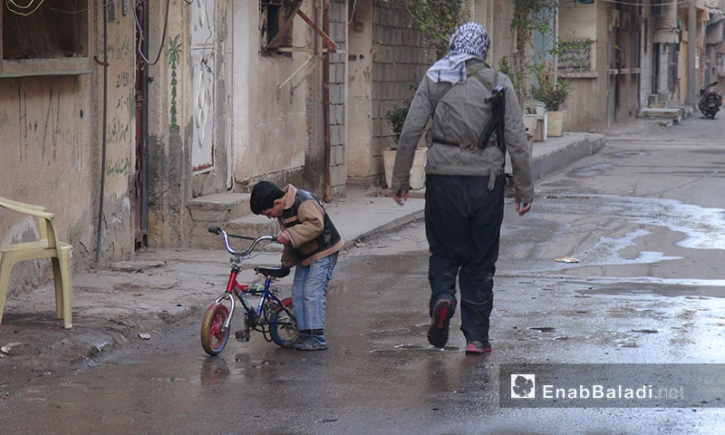 طفل مع مقاتل حي الشيخ ياسين في دير الزور - 2013 (أرشيف عنب بلدي)