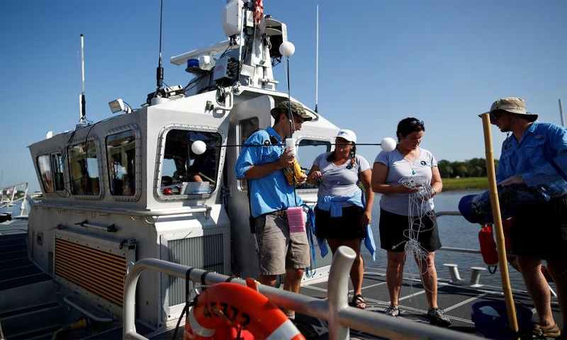 متطوعون من كلية تشارلستون في ساوث كارولاينا قبل اختبار لاطلاق منطاد لالتقاط وقائع الكسوف الشمسي على متن قارب تابع لإدارة خفر السواحل الأمريكية- 17 أغسطس آب 2017 - (رويترز)