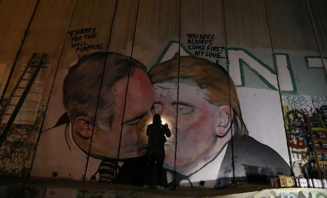 الفنان الاسترالي أثناء رسمه غرافيتي يُظهر قبلة متبادلة بين ترامب ونتنياهو - 28 تشرين الأول (رويترز)