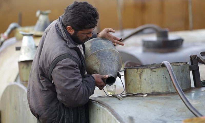 عامل يقوم بتفقد المنتج النهائي للنفط في ريف إدلب- كانون الأول 2015 - (رويترز)

