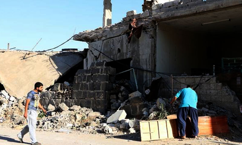 رجال يتفقدون منازلهم في درعا بعد قصف النظام الأسد- حزيران 2017 (الأناضول)
