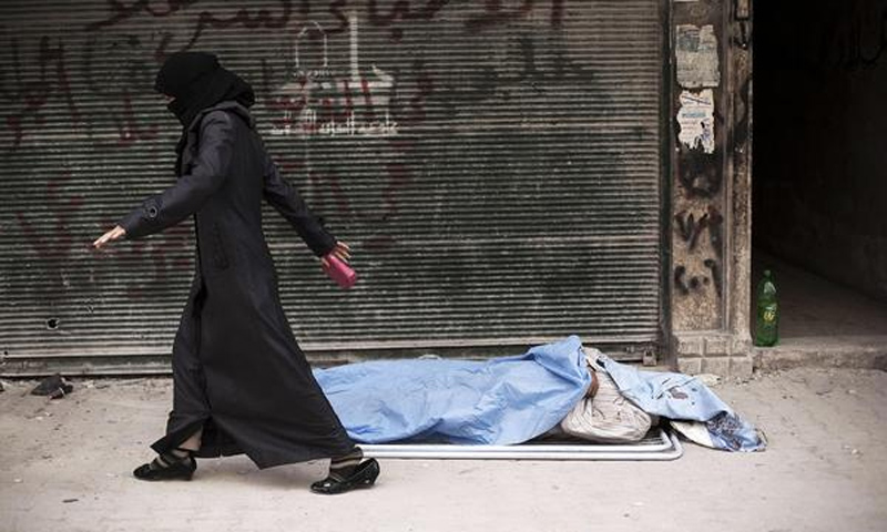 امرأة سورية تمشي أمام جثة مقابل دار الشفاء في مدينة حلب - 10 تشرين الأول 2012 (AFP)

