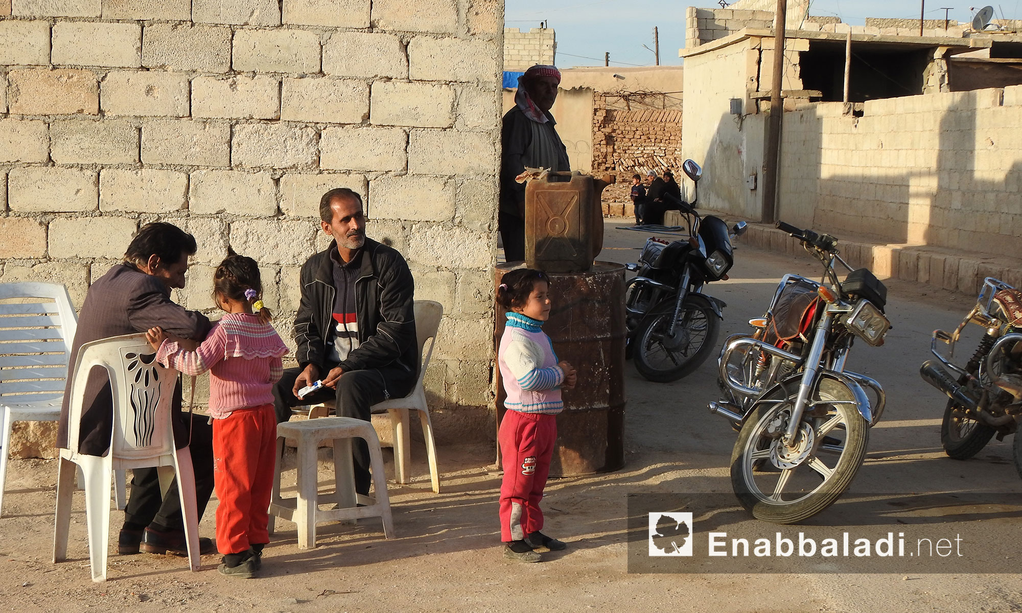 رجال وأطفال يجلسون أمام منازلهم في قرية دوديان بريف حلب الشمالي - 10 كانون الثاني 2018 (عنب بلدي)