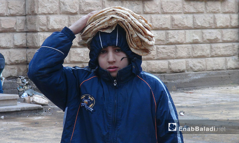 طفل يحمل خبزًا فوق رأسه في حي الحميدية بدير الزور - 2013 (عنب بلدي)
