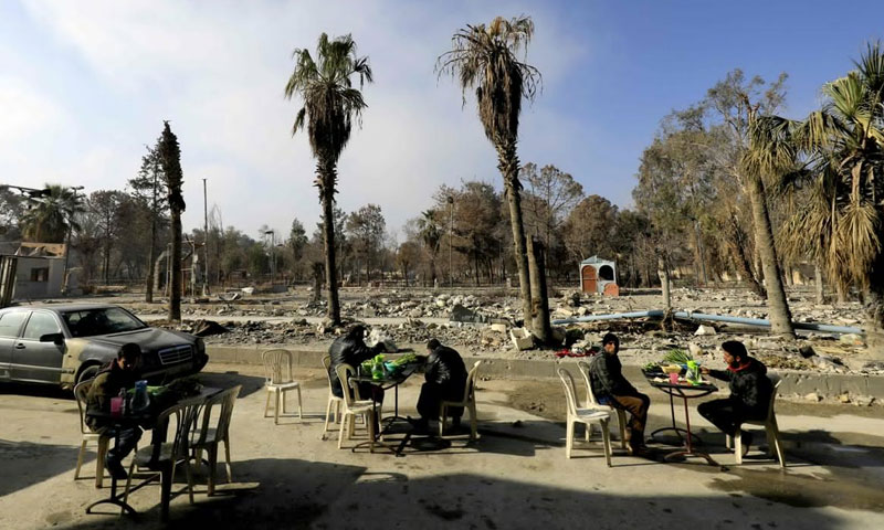 أهالي في مدينة الرقة يجلسون لتناول الطعام وسط الدمار - 2018 (AFP)
