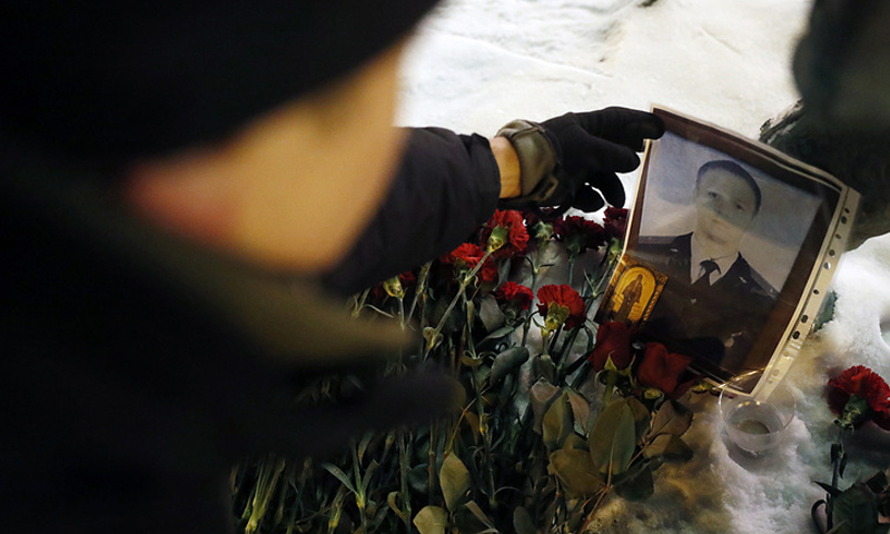 جندي روسي يضع زهور فوق جثمان الطيار الروسي رومان فيليبوف - (تاس)