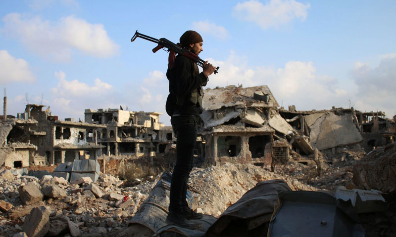مقاتل في الجيش الحر يقف وسط أنقاض المباني المدمرة في مدينة درعا (AFP)
